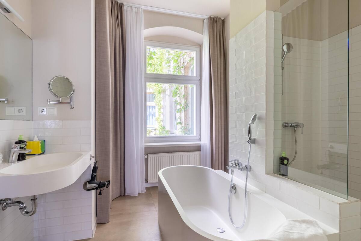 Un baño moderno con una bañera independiente, un tocador doble y cabina de ducha con paredes de cristal.