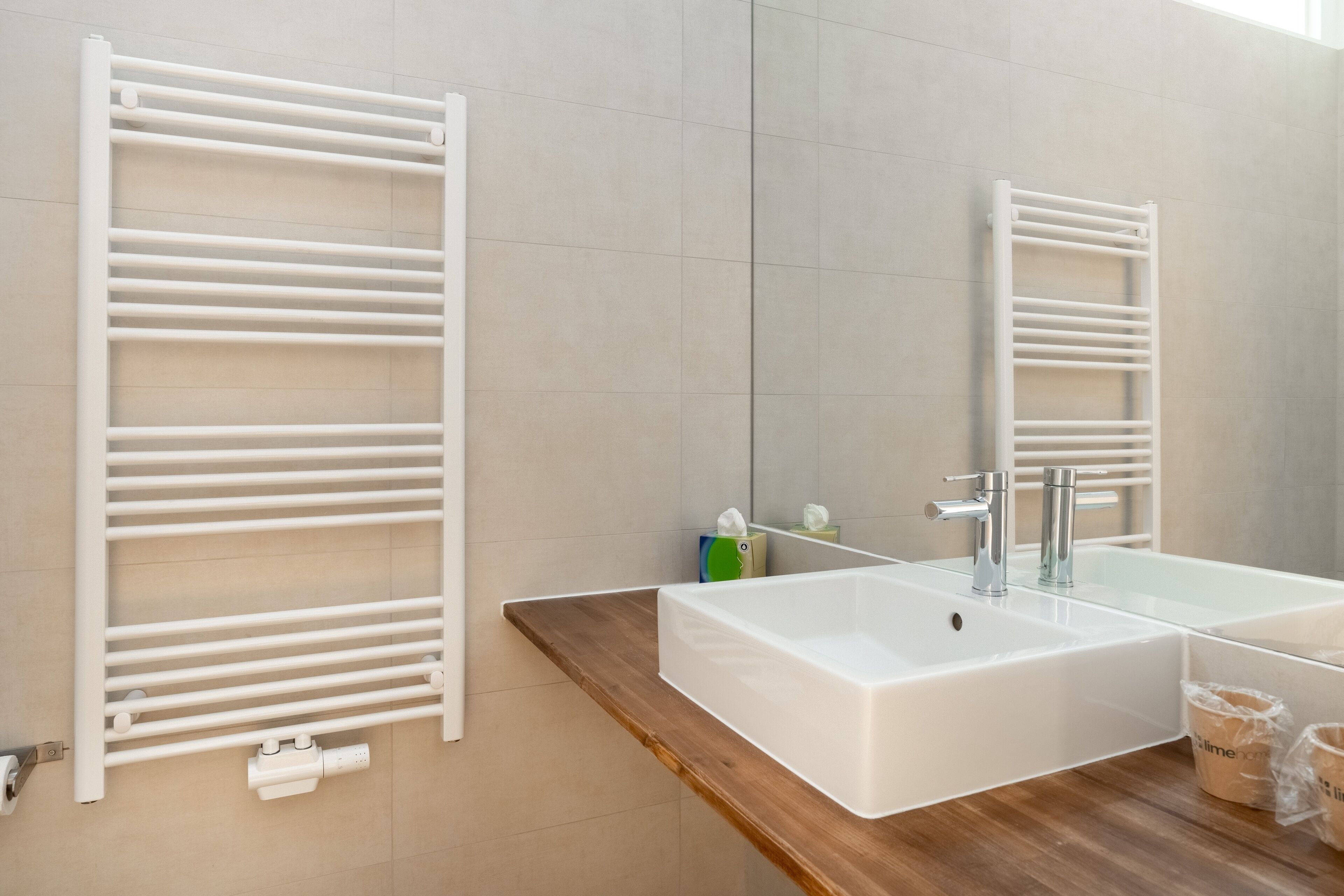 Ein Badezimmer mit einem weißen Waschbecken, einem Spiegel und einem Handtuchhalter.