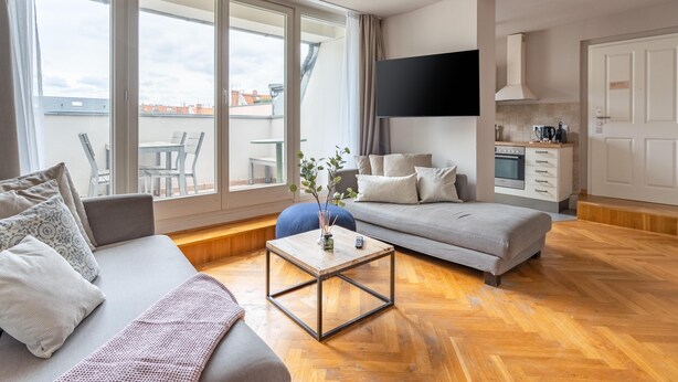 Una sala de estar moderna con un sofá, una mesa de centro y un televisor montado en la pared.