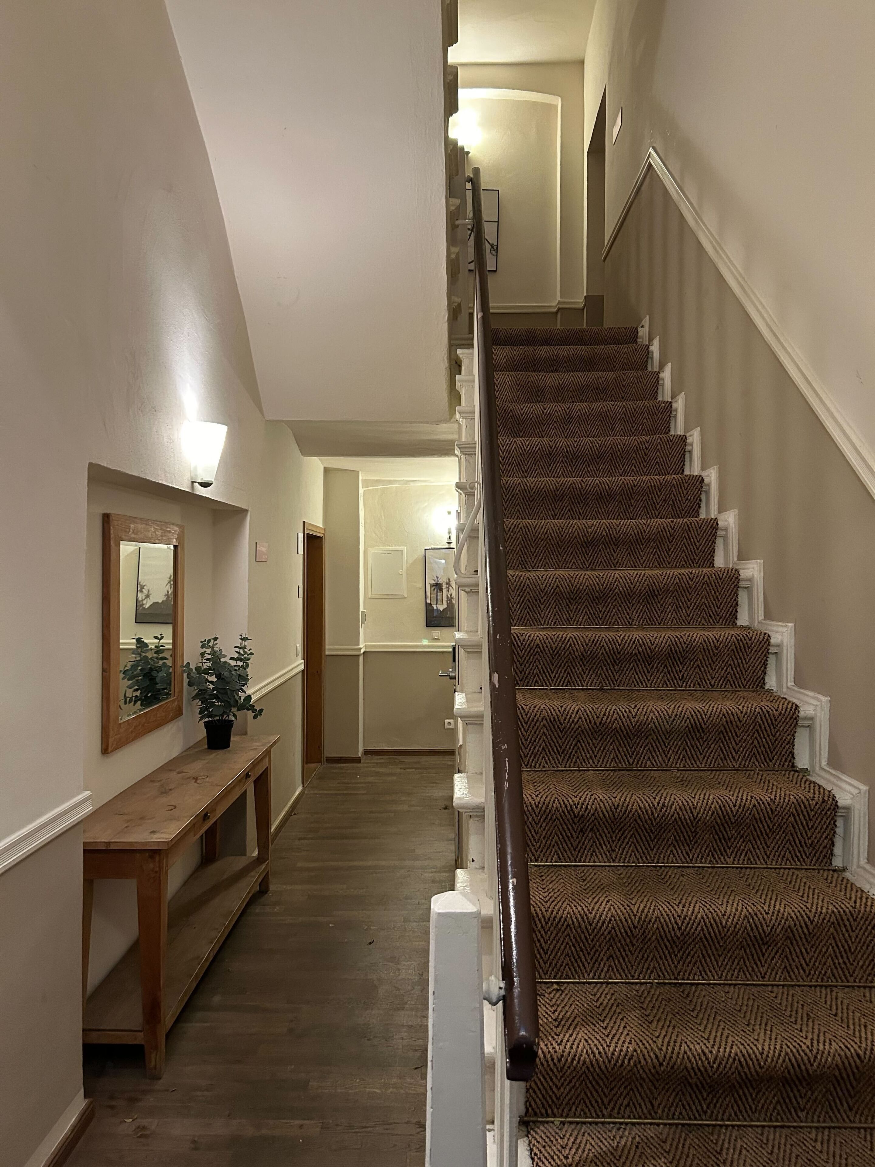 A staircase with patterned carpet and white balusters, leading to a door at the top.