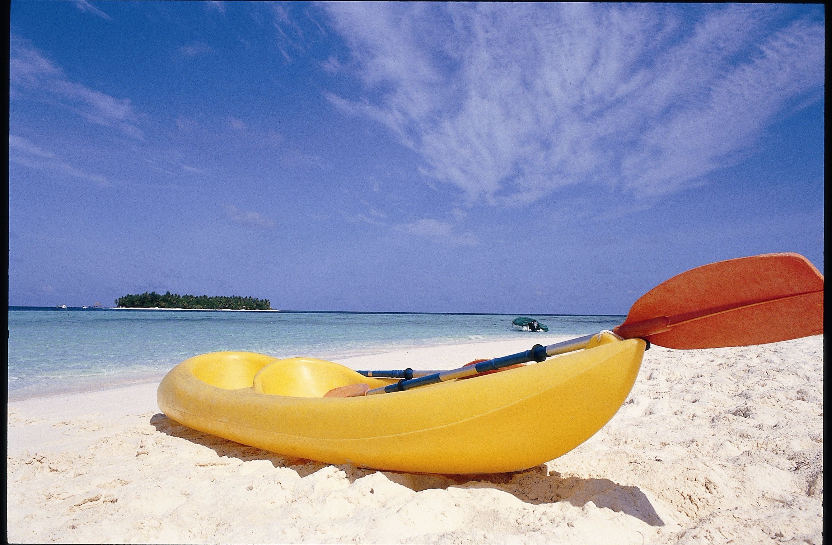 A yellow inflatable raft on a sandy beach with a clear blue sky and calm sea.
