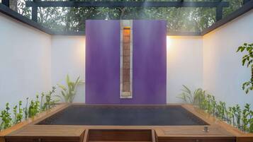 Un área de spa moderna con un banco de madera, una pared morada y una ventana pequeña.