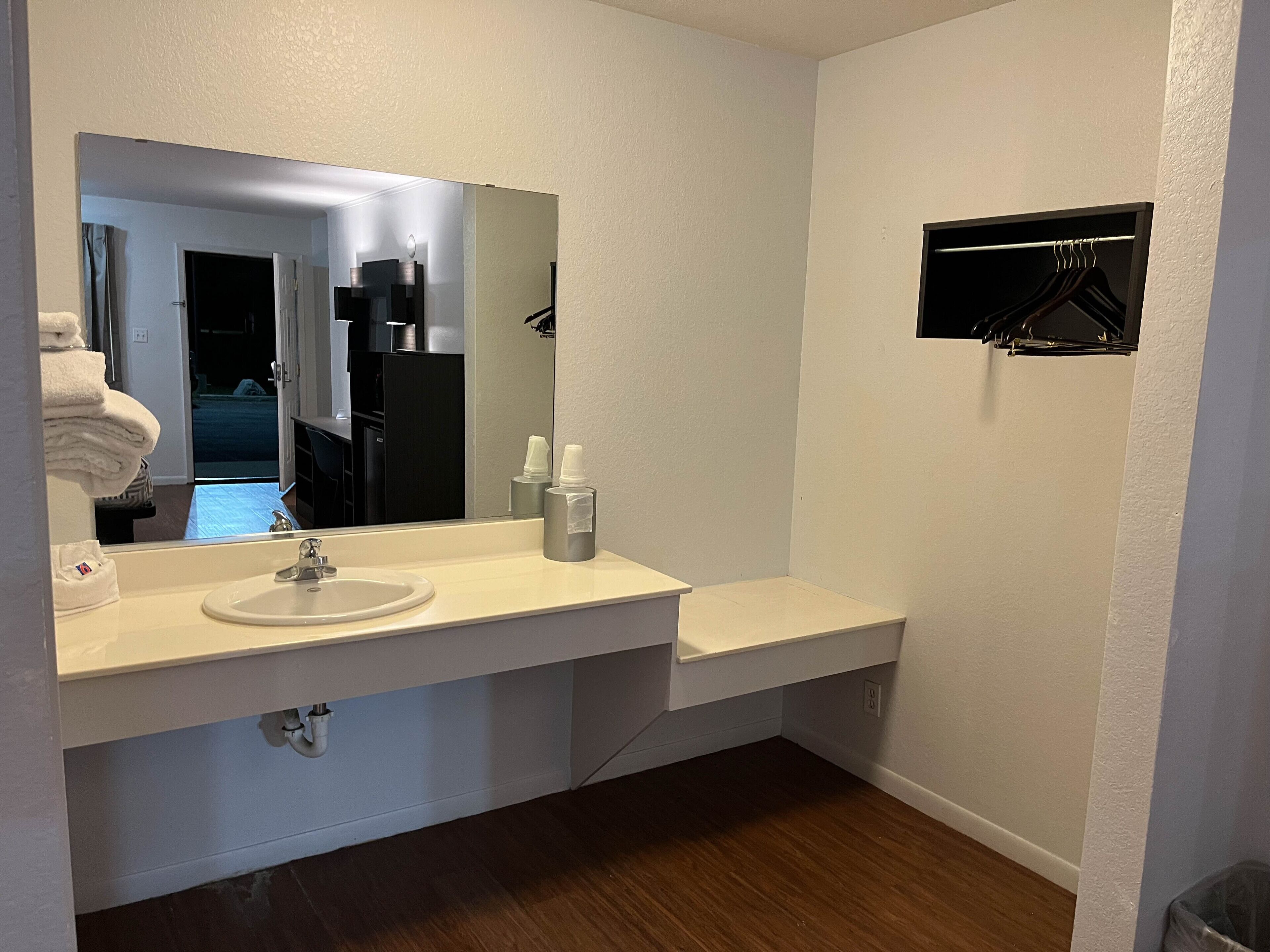 A bathroom with a white sink, mirror, and a small shelf with toiletries.