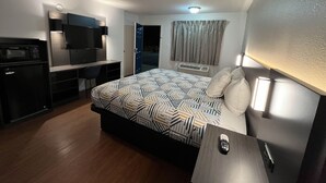 A hotel room with a bed, a desk with a TV, a microwave, and a wardrobe. - Motel 6 Junction, Texas - Llano River (Junction)