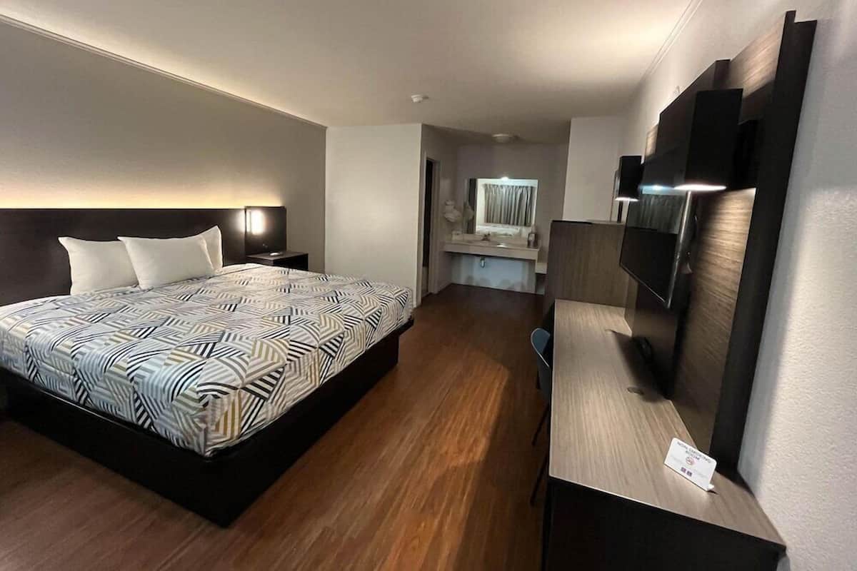 A hotel room with a bed, a desk, a TV, and a mirror.