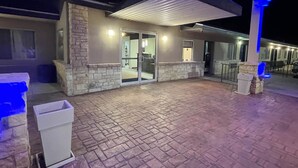 A modern building with a stone facade, a covered patio area, and a glass entrance. - Motel 6 Junction, Texas - Llano River (Junction)