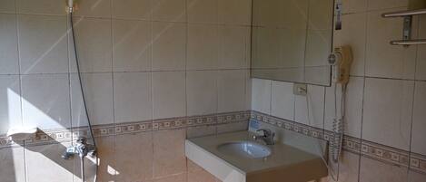 A bathroom with a sink, mirror, and shower.