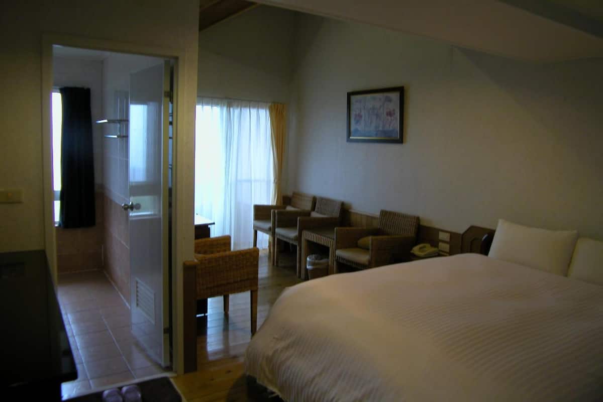 A bedroom with a large bed, a small table, two chairs, and a sofa.