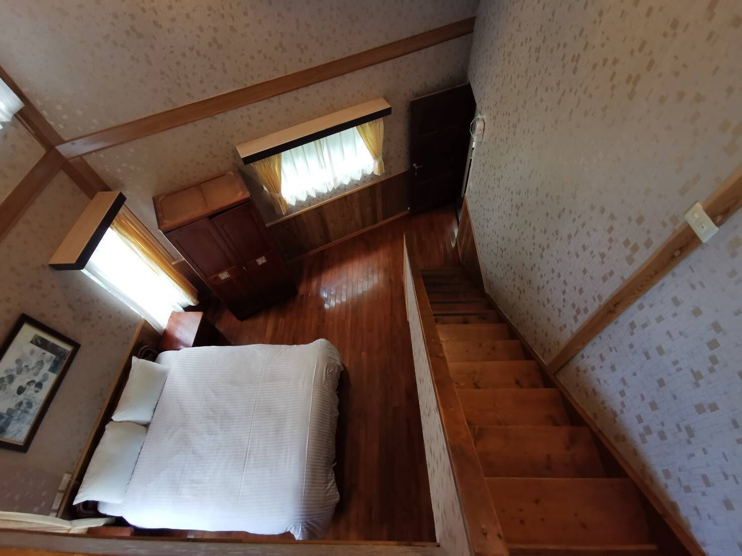 A bedroom with a bed, a nightstand, a dresser, and a window with curtains.