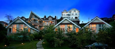 A modern residential complex with multiple houses, a well-maintained lawn, and a pathway leading to the entrance.
