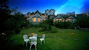 A large, multi-story house with a well-maintained lawn and outdoor seating area. - Dream Town (Ren'ai)