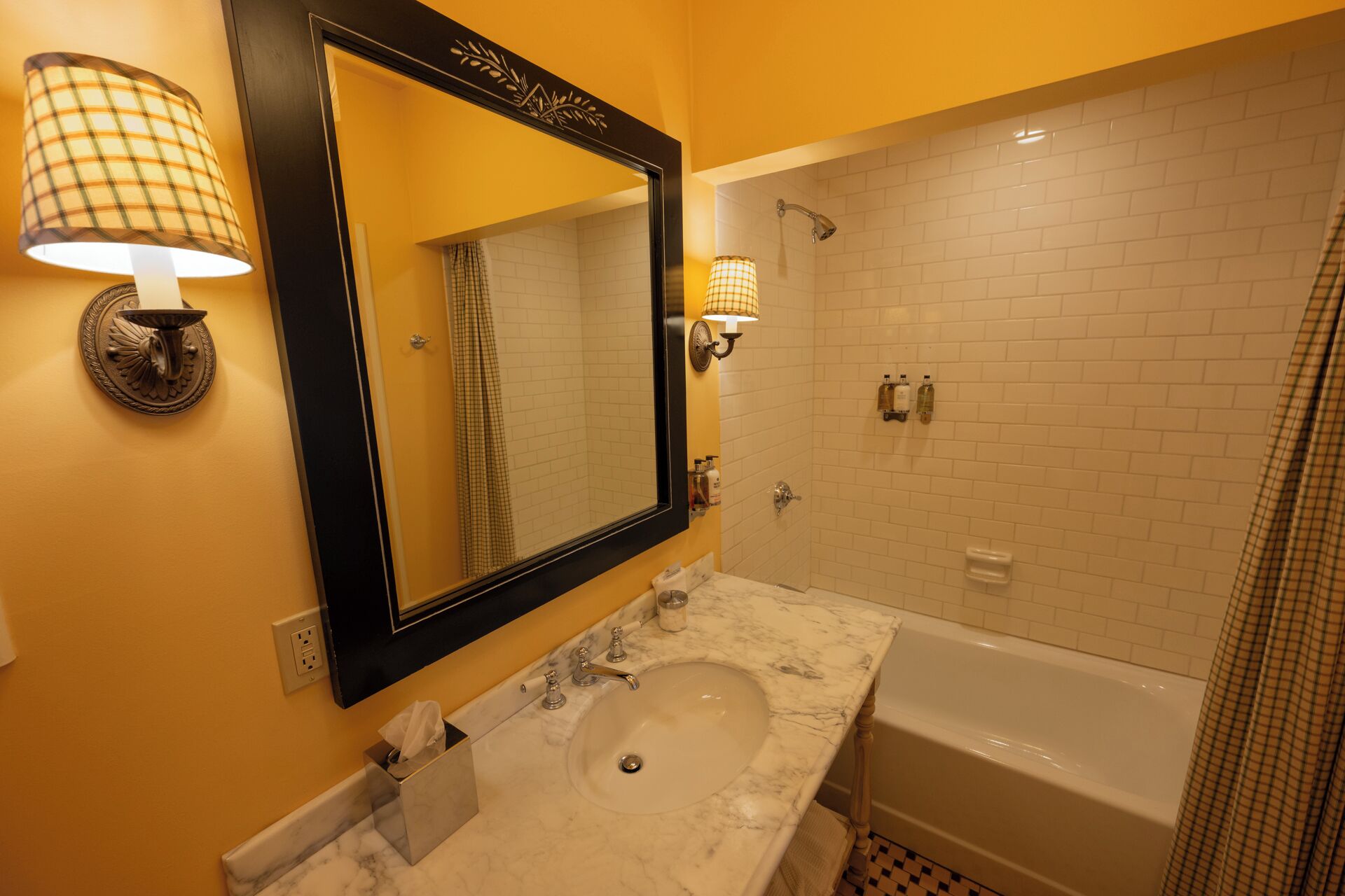 A bathroom with a large mirror, a sink, and a bathtub.