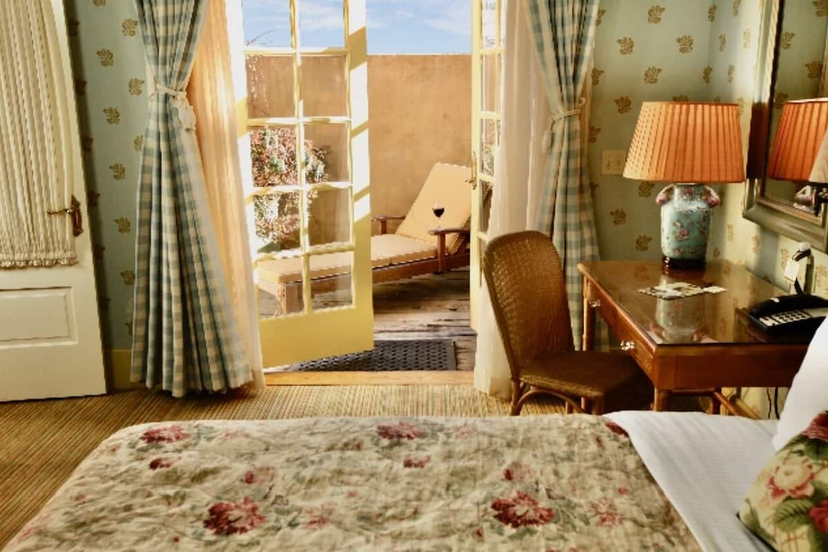 A hotel room with a bed, a desk, a chair, and a window with curtains.