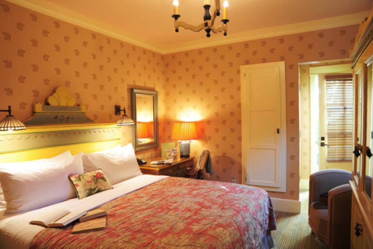 A hotel room with a bed, bedside lamps, a nightstand, a chair, a door, and a window with blinds.