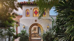 A building with a tiled roof, a stone wall, and a pathway leading to an arched entrance. - Lucille Palm Springs (Palm Springs)