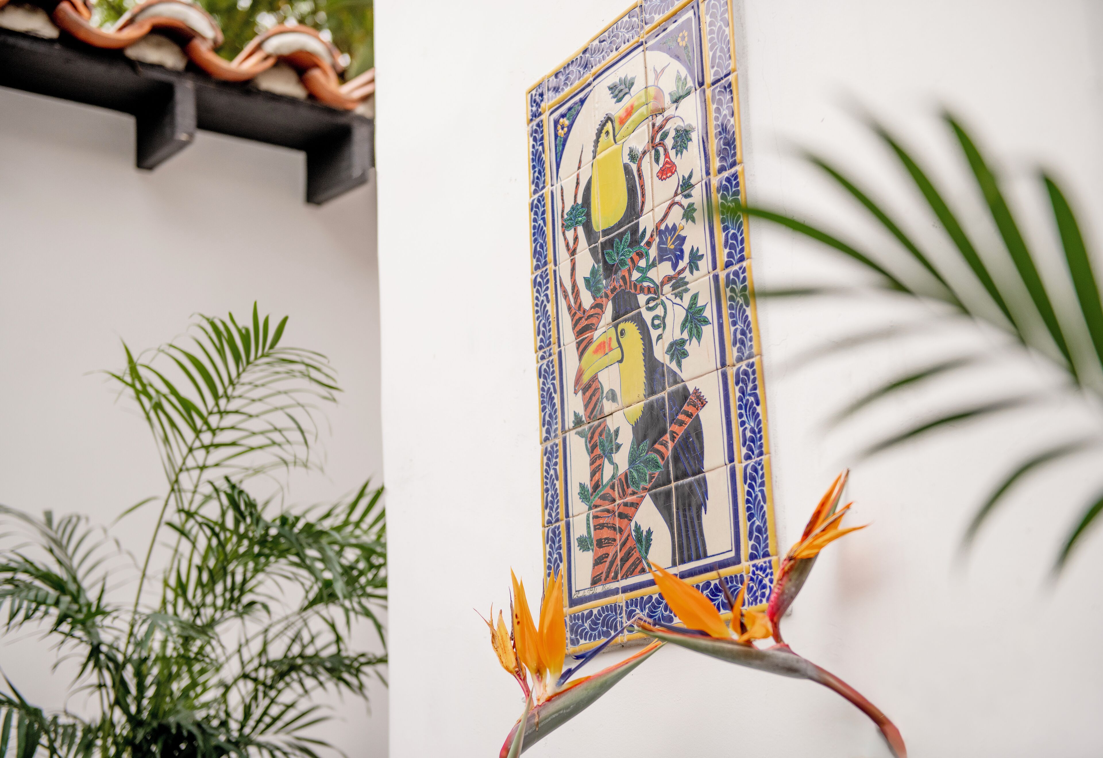 A tiled wall with a bird of paradise flower and a plant.