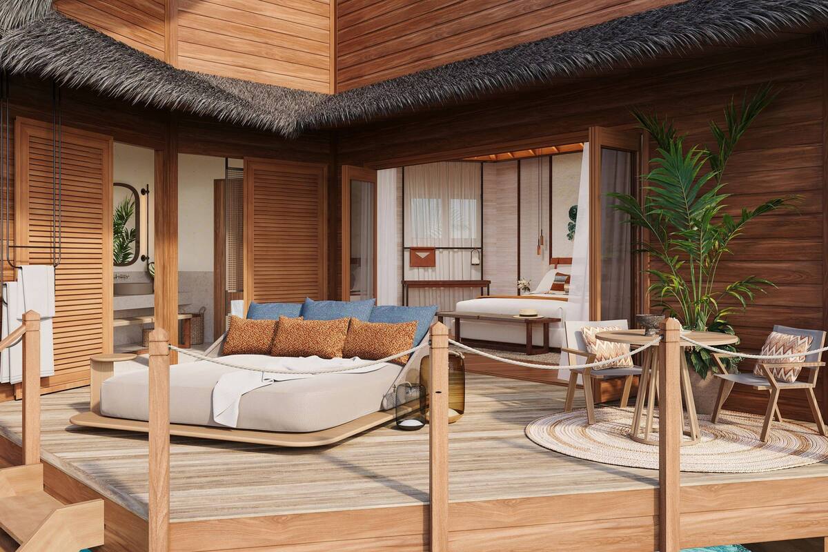 A wooden deck with a bed, a dining area, and a view of the ocean.