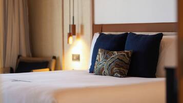 A hotel room with a bed, a chair, and a wall-mounted light fixture.