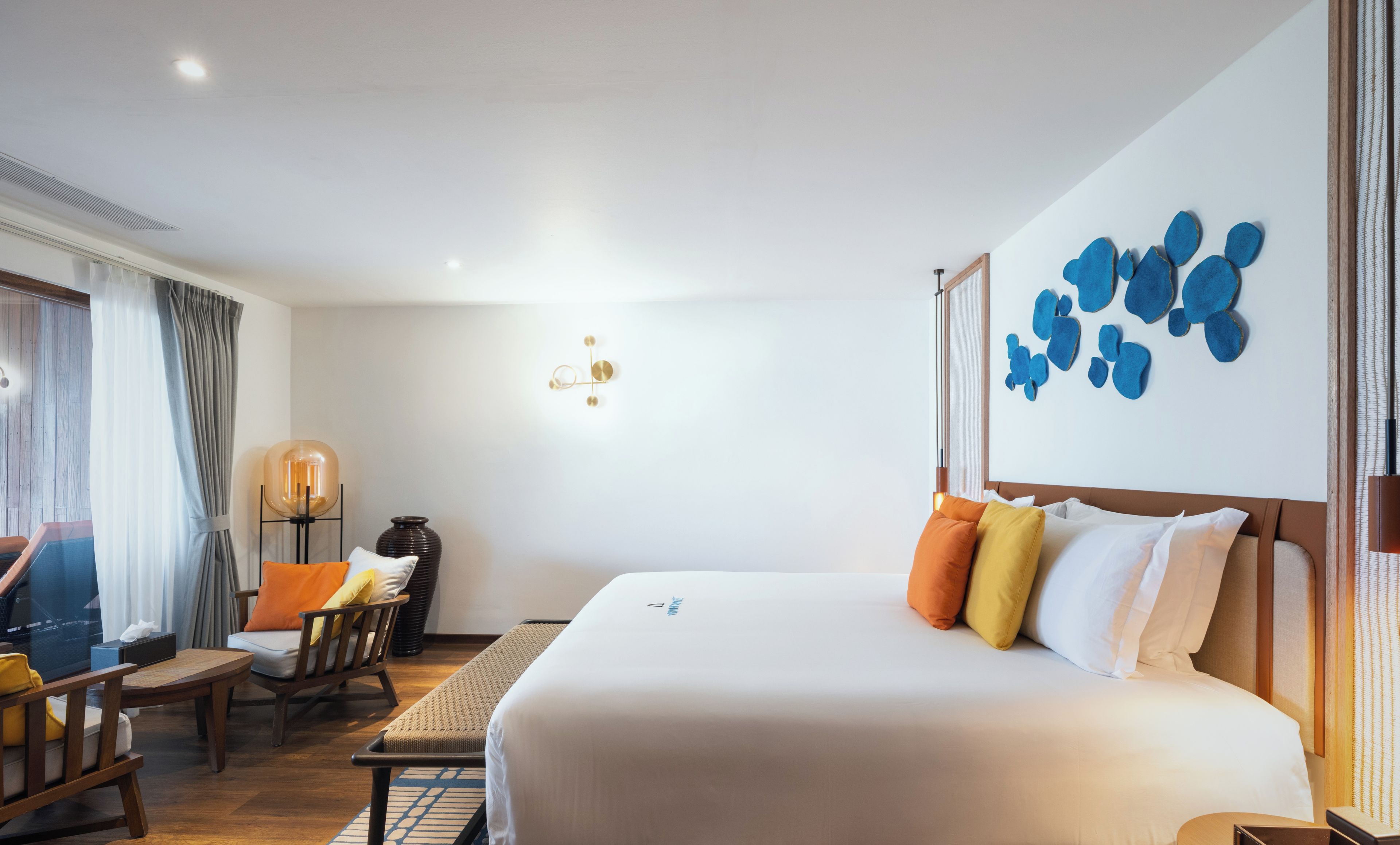 Una habitación de hotel con cama, escritorio, silla, lámpara y decoración en la pared.