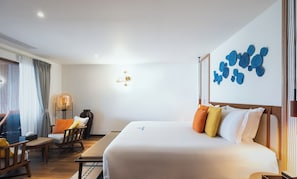 A hotel room with a bed, a desk, a chair, a lamp, and a wall decoration. - V Villas Maldives at Mirihi - MGallery Collection (Mirihi)