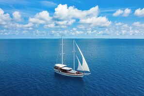 A sailboat on calm blue waters with a clear sky.