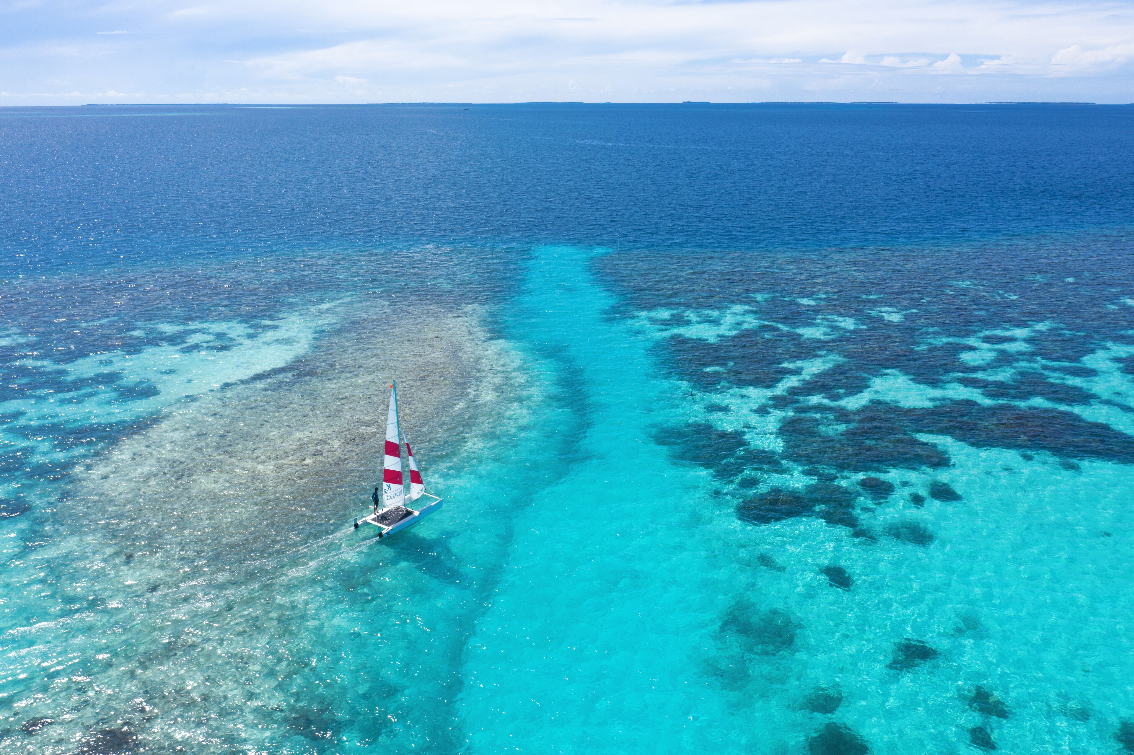Un velero en un mar turquesa transparente con arrecifes de coral.