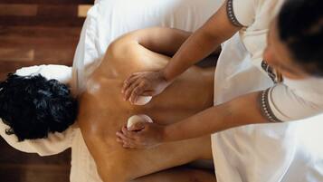 A person receiving a back massage in a room with a wooden floor.