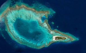 An aerial view of a tropical island with clear waters, a central lagoon, and a small resort area with buildings and pathways. - V Villas Maldives at Mirihi - MGallery Collection (Mirihi)