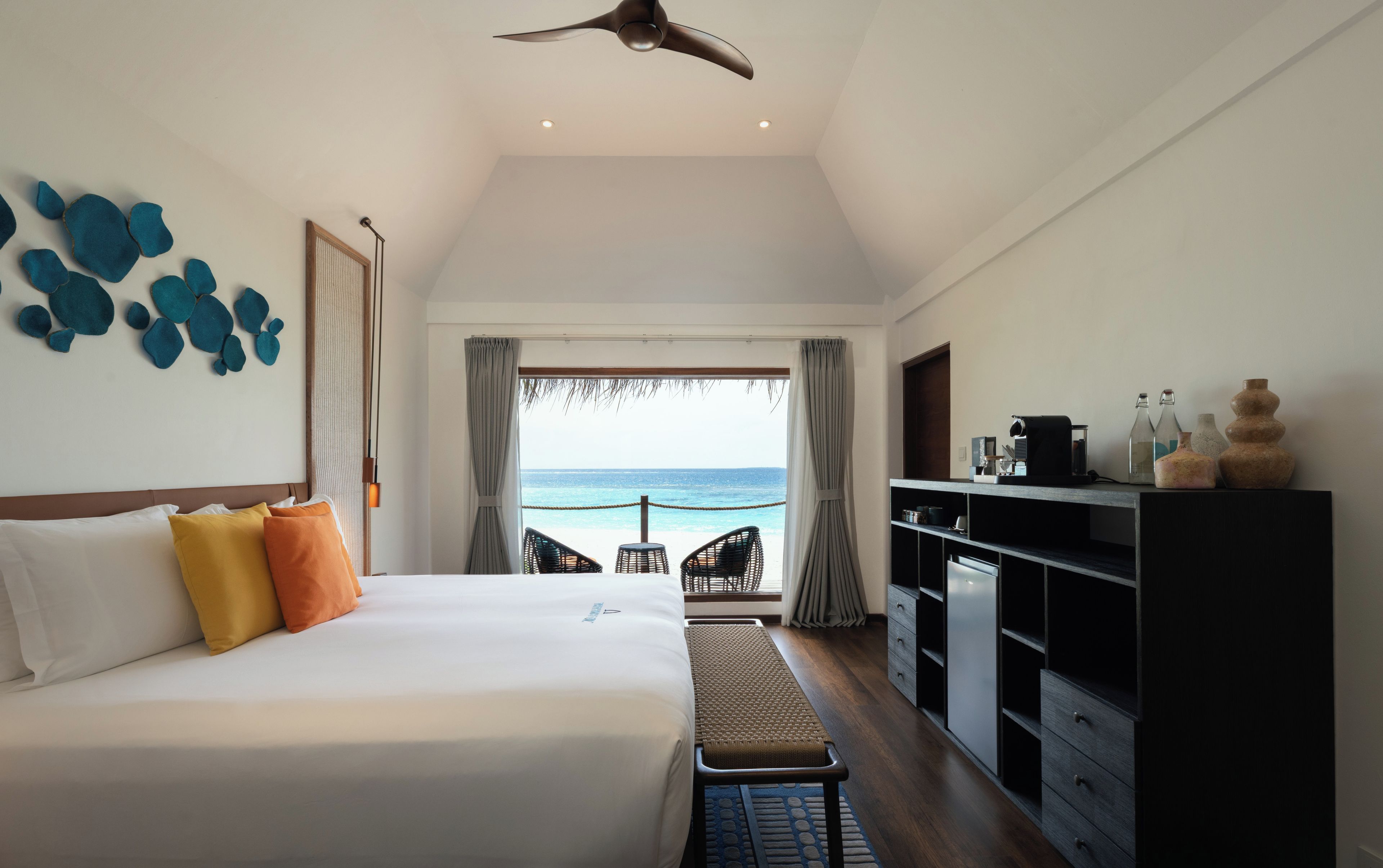 Una habitación de hotel con cama, escritorio y vista al océano.