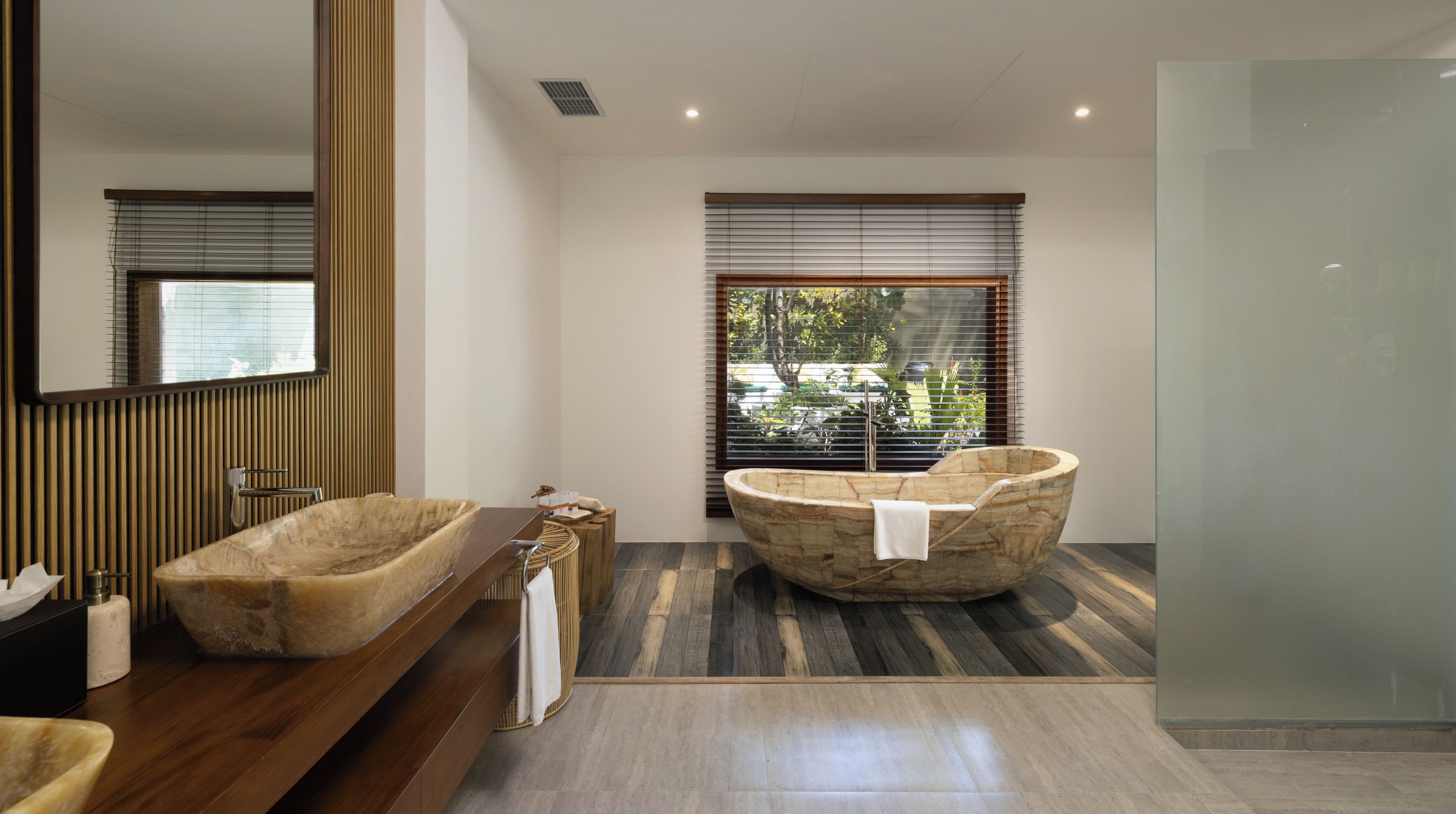 A modern bathroom with a freestanding bathtub, a wooden vanity, and a large mirror.