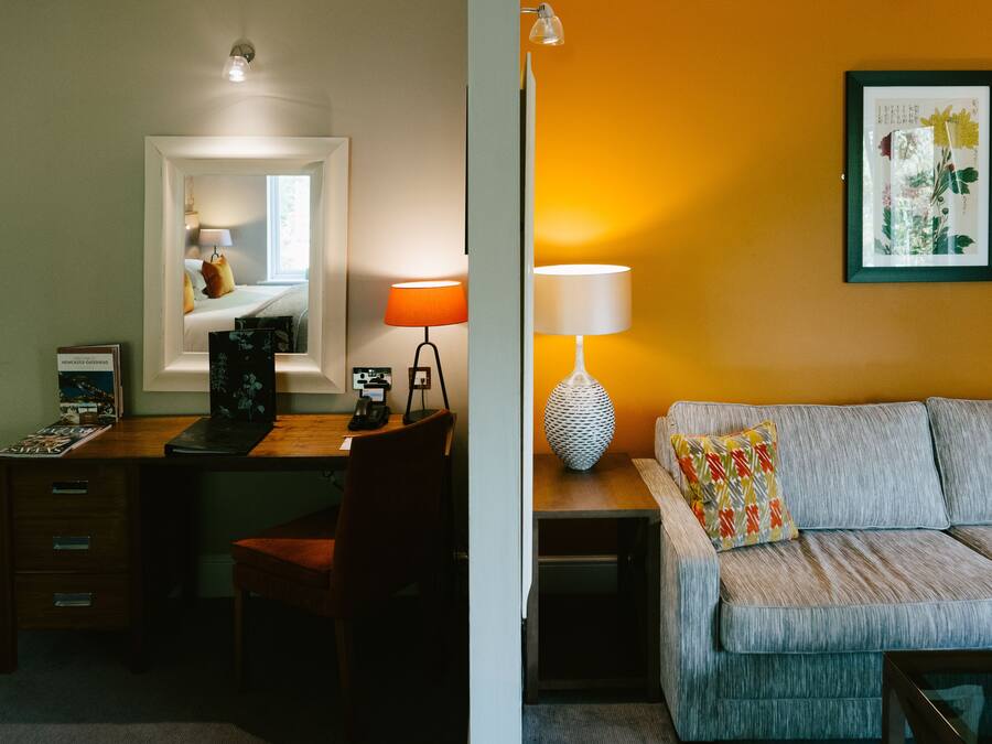 Una habitación con escritorio, silla y sofá con cojín.