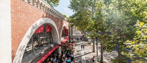 Un café doté d’une terrasse, d’une façade en briques et d’une allée couverte.