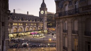 Un edificio histórico con una torre del reloj, un patio central y arquitectura moderna circundante.