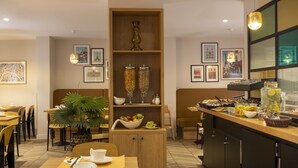 Un comedor moderno con muebles de madera, una barra de buffet con diversos alimentos y cuadros en las paredes.