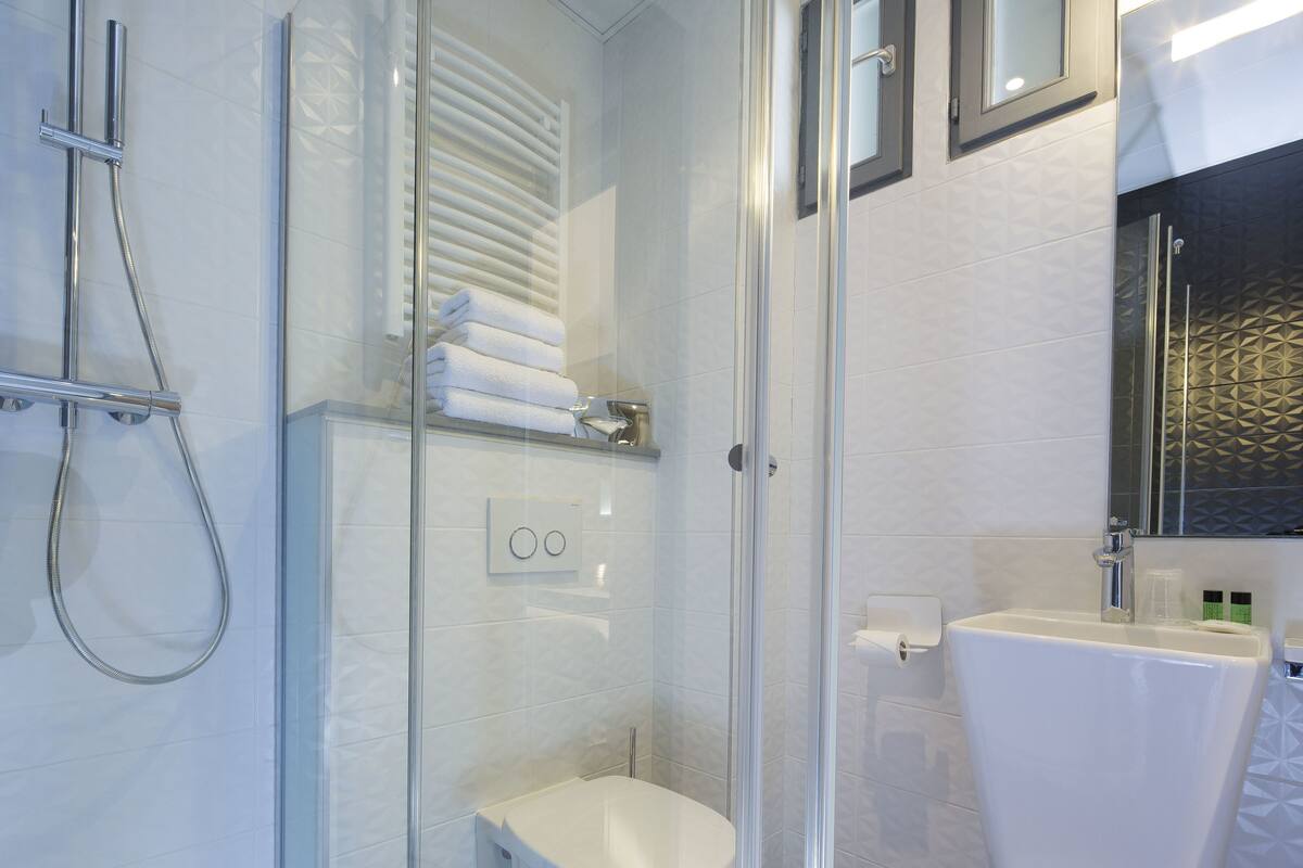 A modern bathroom with a glass-enclosed shower, a white toilet, and a sink with a mirror above.