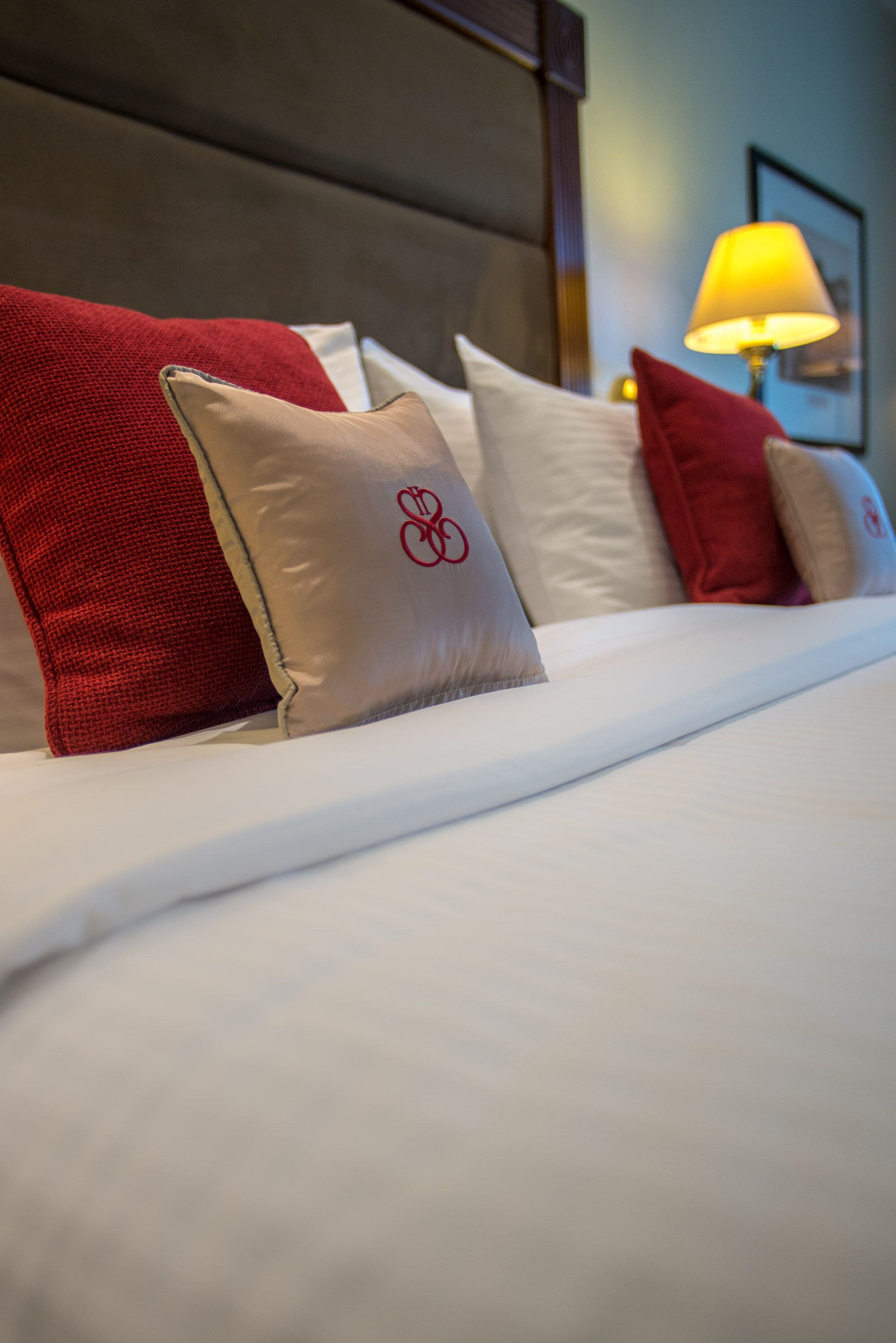 Una cama bien hecha con una variedad de almohadas, algunas con un logotipo rojo.