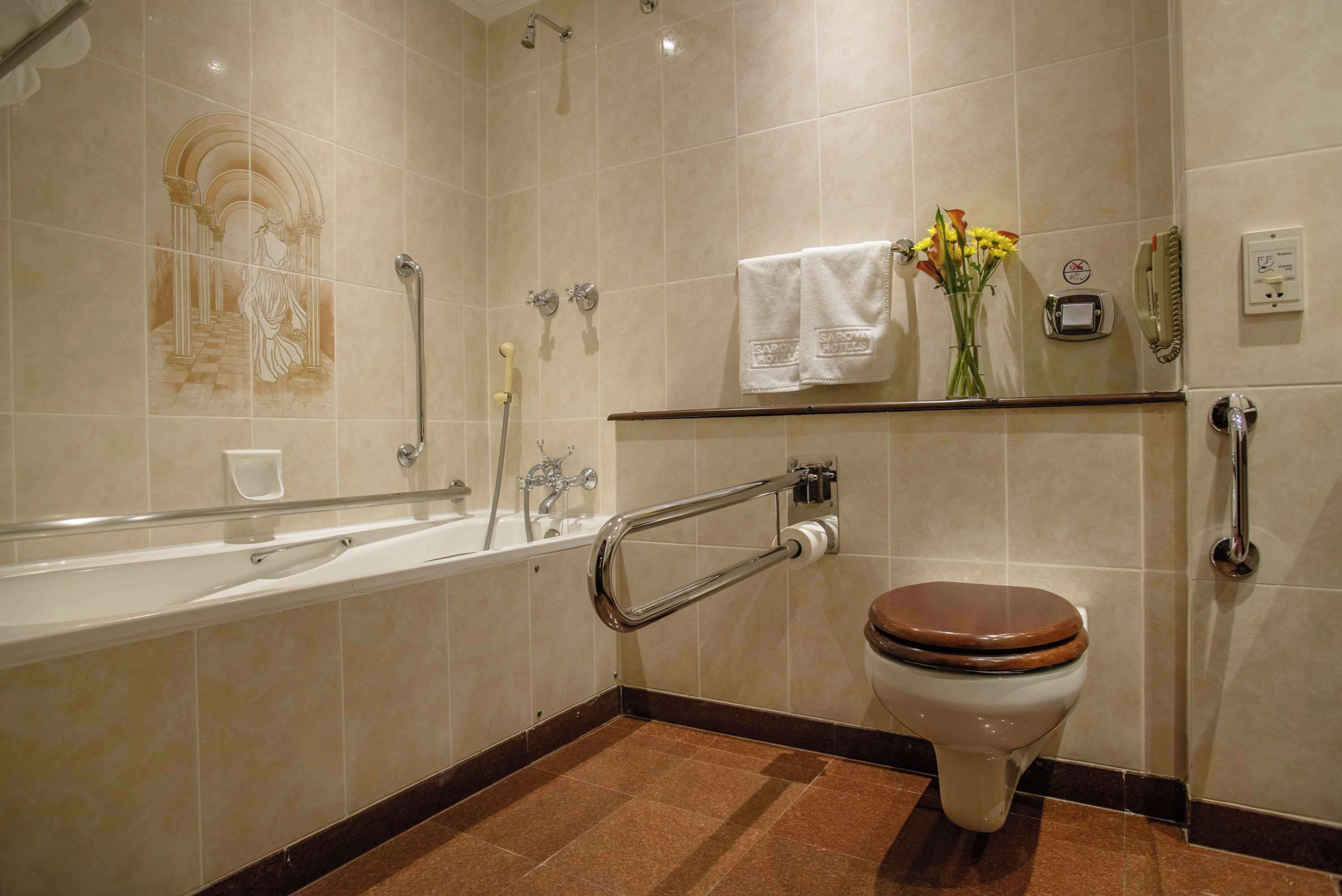 Un baño con bañera, inodoro y barras de apoyo.
