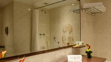 A bathroom with a marble sink, a large mirror, a shower, and a towel rack.
