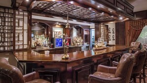 A bar area with a wooden counter, leather bar stools, and various bottles and glasses. - Sarova Stanley Hotel, Nairobi (Nairobi)
