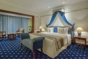 A hotel room with a large bed, two bedside tables, a chair, and a small table.