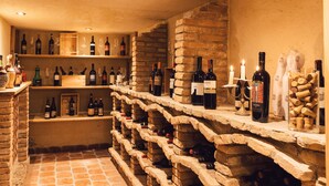 Une cave à vin avec des étagères en pierre où sont rangées des bouteilles de vin et des verres.