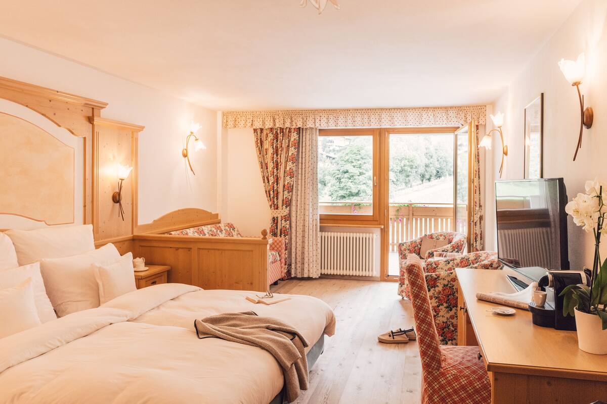 Hotelkamer met een bed, een bureau, een stoel, een televisie en een raam met gordijnen.
