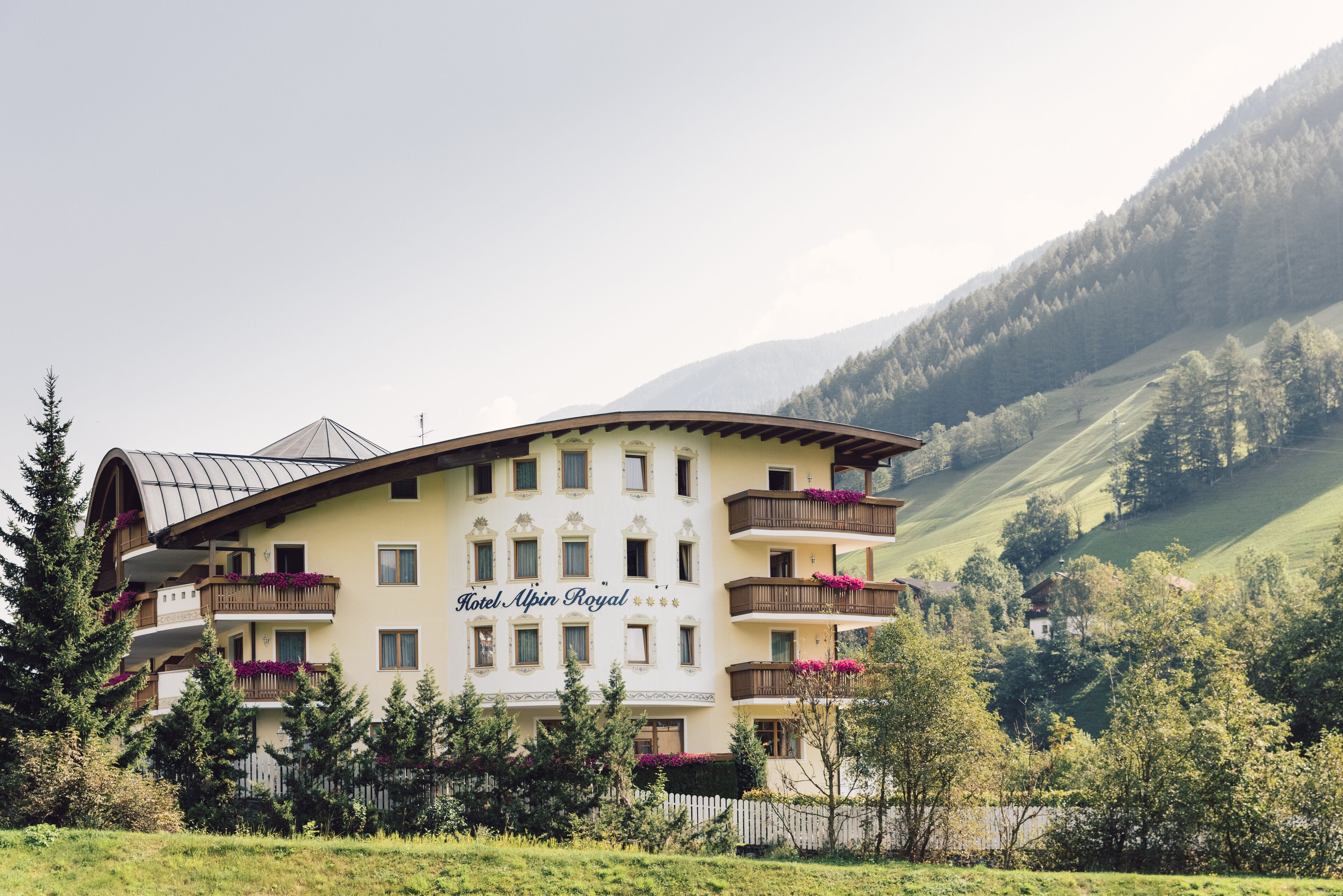 A hotel with multiple balconies, a curved roof, and a mountainous backdrop.