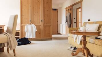 A room with a large wooden wardrobe, a sofa, a small round table, and a chair.