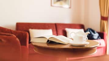 Ein gemütliches Zimmer mit einer roten Couch, einem kleinen Tisch mit Teekanne und Buch.
