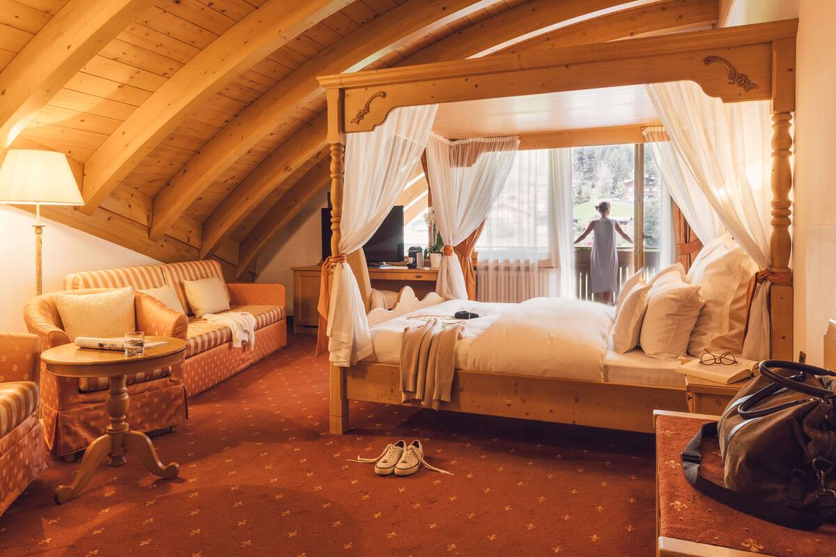 Een knus slaapkamer met een hemelbed, een bank, een klein tafeltje en een stoel.