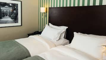 Une chambre d’hôtel avec deux lits, un tableau encadré au mur et une table de chevet avec une lampe.