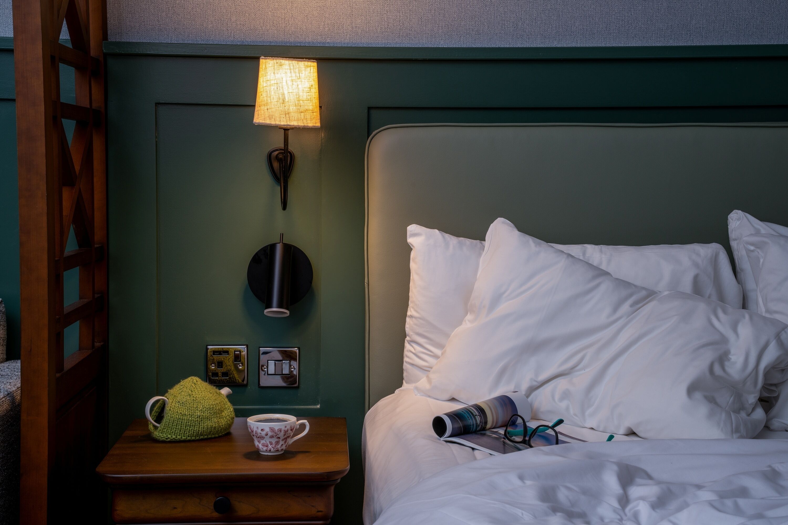 Un lit bien fait, avec des oreillers blancs et une lampe sur une table de chevet.