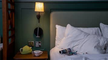 Un lit bien fait, avec des oreillers blancs et une lampe sur une table de chevet.