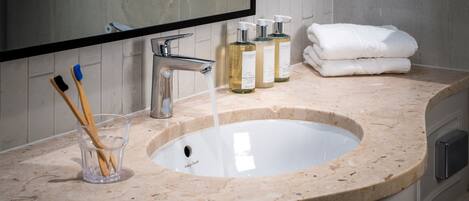 Une salle de bain équipée d’un lavabo, d’un miroir, d’articles de toilette et de serviettes.